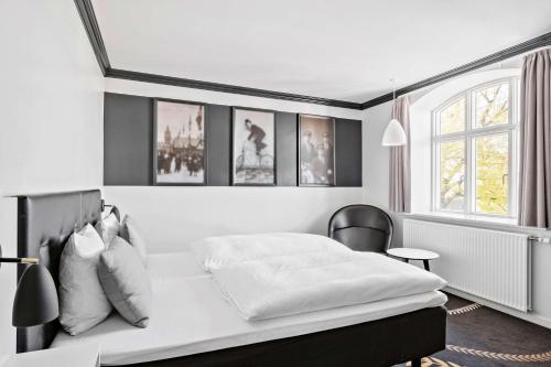 a white bedroom with a bed and a chair at Best Western Plus Hotel Eyde in Herning