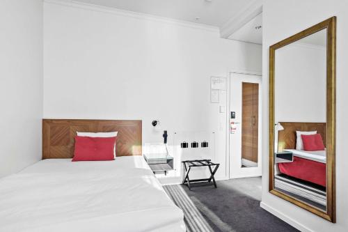 a bedroom with a large white bed and a mirror at Best Western Plus Hotel Eyde in Herning