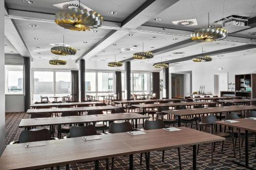 a restaurant with wooden tables and chairs and windows at Best Western Plus Hotel Eyde in Herning