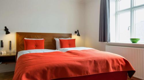 a bedroom with a bed with red sheets and a window at Best Western Plus Hotel Eyde in Herning