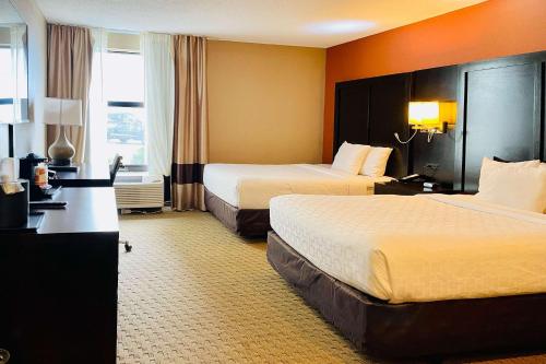 a hotel room with two beds and a desk at Clarion Inn & Suites in Evansville