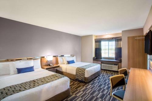 a hotel room with two beds and a television at Microtel Inn & Suites by Wyndham Vernal/Naples in Vernal