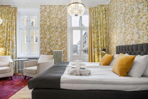 a bedroom with a large white bed with yellow curtains at Hotell Linnéa - Helsingborg in Helsingborg