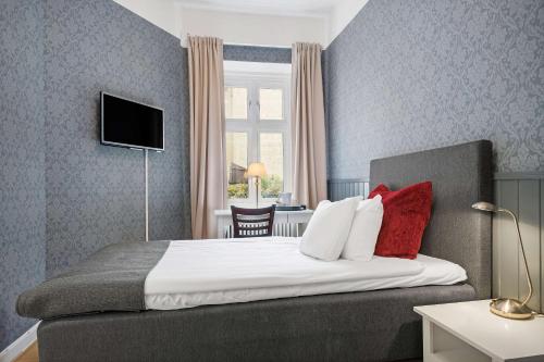 a hotel room with a large bed with red pillows at Hotell Linnéa - Helsingborg in Helsingborg