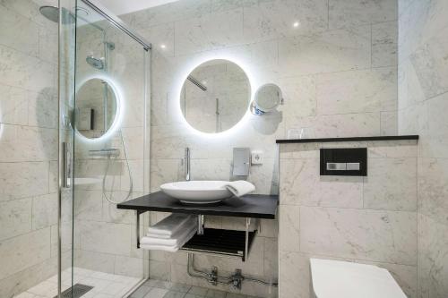 a bathroom with a sink and a glass shower at Hotell Linnéa - Helsingborg in Helsingborg