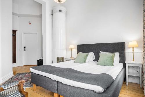 a bedroom with a large bed with green pillows at Hotell Linnéa - Helsingborg in Helsingborg
