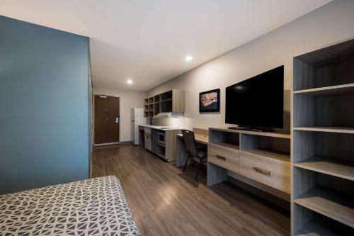 a bedroom with a bed and a desk with a television at WoodSpring Suites Wixom - Novi in Wixom