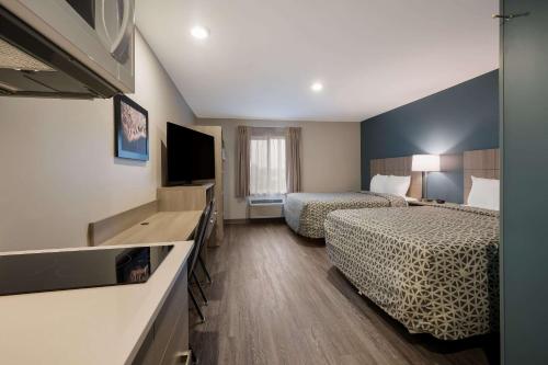 a hotel room with two beds and a flat screen tv at WoodSpring Suites Wixom - Novi in Wixom