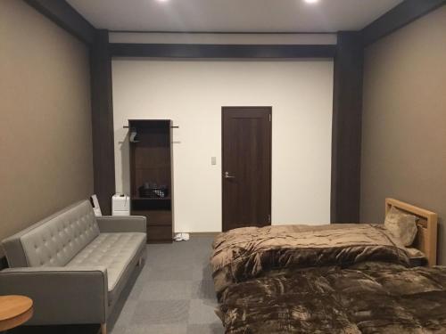 1 dormitorio con cama, sofá y puerta en Iitoko - Vacation STAY 43906v, en Iitoyo