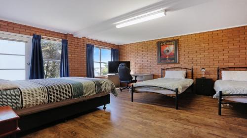 a bedroom with two beds and a chair and a television at 8 Carolynne Street, Merimbula in Merimbula