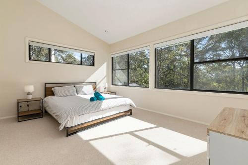 a bedroom with windows and a bed with a teddy bear on it at Treescape by the Lake in Murrays Beach
