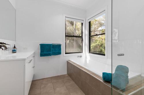a white bathroom with a tub and a window at Treescape by the Lake in Murrays Beach