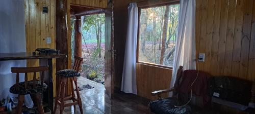 a room with a window and two chairs in a house at Cabañas Libertad en Misiones in Puerto Bossetti