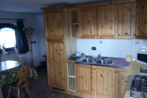 eine Küche mit Holzschränken und einem Waschbecken in der Unterkunft Chapelle - appartamento A in Sommarese