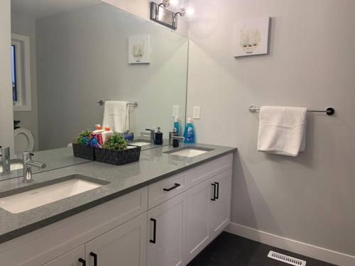 a bathroom with two sinks and a large mirror at Luxurious 3 BR Villa with free parking - King Bed in Regina