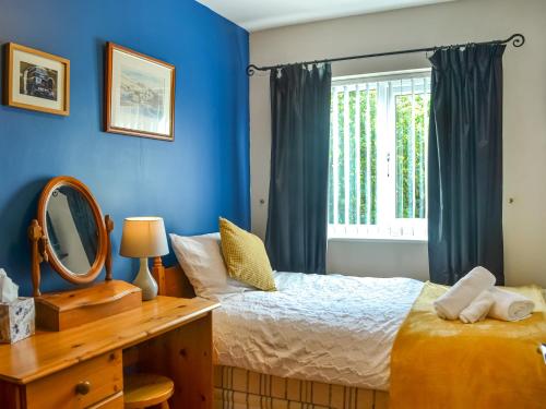 una camera da letto con pareti blu, un letto e uno specchio di Rowan House a Beverley