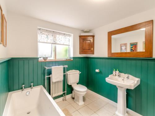 a bathroom with a tub and a toilet and a sink at Workshop Cottage in Rawcliffe