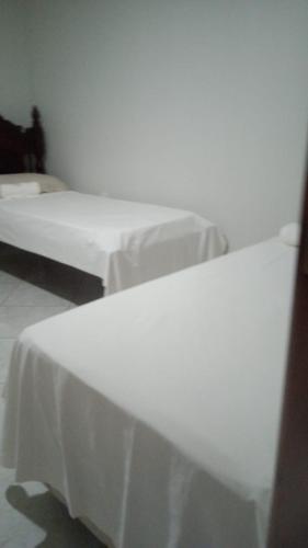 two beds in a room with white sheets at Pousada Balsas in Balsas