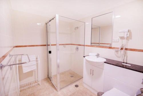 a white bathroom with a shower and a sink at PI702 - Ideally Located Sydney CBD in Sydney