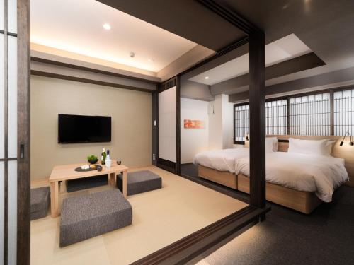 a bedroom with a bed and a table and a tv at MIMARU Kyoto Nishinotoin Takatsuji in Kyoto