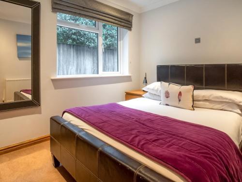 a bedroom with a large bed and a mirror at Lawn Lodge in Brockenhurst