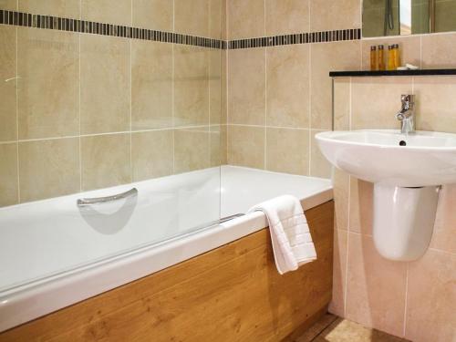 a bathroom with a sink and a bath tub and a sink at Lawn Lodge in Brockenhurst