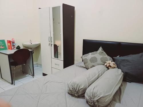 Schlafzimmer mit einem Bett mit Kissen und einem Schreibtisch in der Unterkunft Kost Griya Asri by ecommerceloka in Jakarta