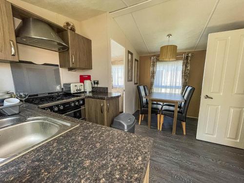 cocina con fregadero y fogones en Lovely 8 Berth Caravan With Decking And Nearby Scratby Beach Ref 50005a en Great Yarmouth