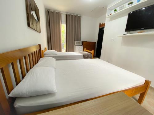 1 dormitorio con 2 camas y TV de pantalla plana en SUÍTE PRIVATIVA RIVIERA & ITAGUARÉ 100mts de 2 praias!, en Bertioga