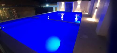 a blue swimming pool in a room with lights at Hospedaje In House in La Merced