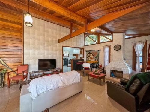 a living room with a bed and a tv and a couch at Cantareira - Deck House in Mairiporã