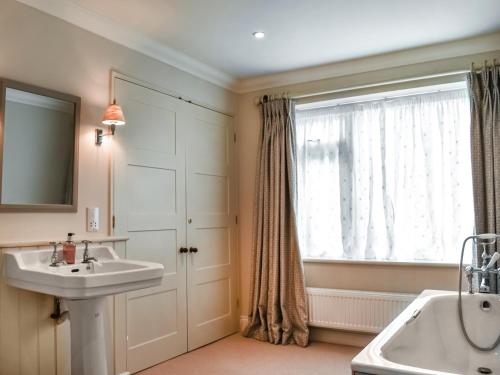 een badkamer met een wastafel, een bad en een raam bij An Croke in Higham