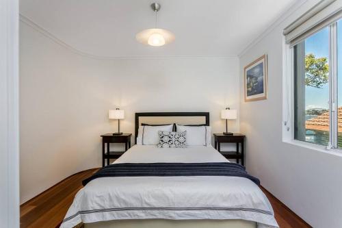 a white bedroom with a bed and two windows at STG38 - stunning waterfront apartment - Drummoyne in Sydney