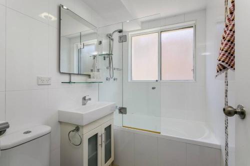 ein weißes Badezimmer mit einem Waschbecken und einem Spiegel in der Unterkunft STG38 - stunning waterfront apartment - Drummoyne in Sydney