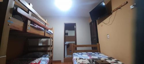1 dormitorio con 2 literas y TV en Hospedaje In House, en La Merced