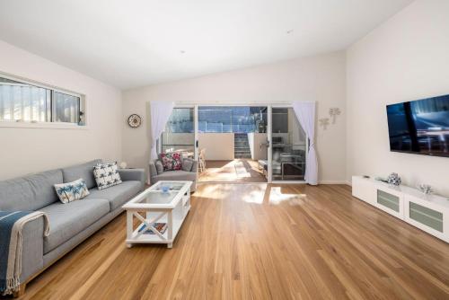 a living room with a couch and a tv at Bentley Beach Villa in Nelson Bay