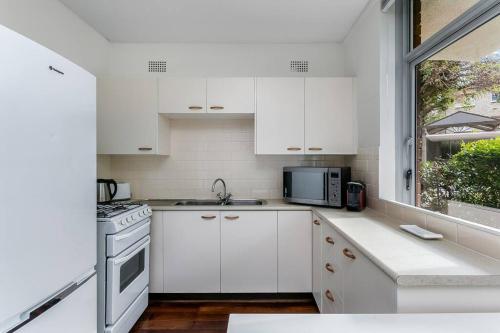 Biała kuchnia z białymi szafkami i oknem w obiekcie YNG03 - Cremorne - Young Street w mieście Sydney