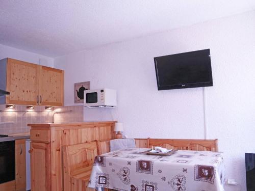 Il comprend une cuisine avec une table et une télévision murale. dans l'établissement Studio skis aux pieds, 4 pers, terrasse ensoleillée, prox commerces et animations - FR-1-322-529, aux Orres