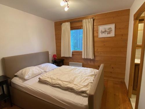 a bed in a bedroom with a wooden wall at Appartement Crest-Voland, 3 pièces, 6 personnes - FR-1-733-140 in Crest-Voland