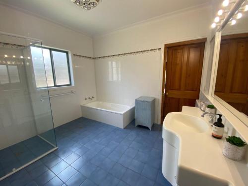 a bathroom with a tub and a sink and a shower at 56 Culgoa Crescent, Pambula Beach in Pambula Beach