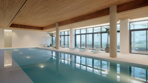 a large swimming pool in a building with windows at The Heaven Resort in Ansan