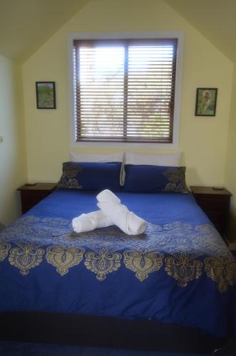 a bed with a blue comforter with two towels on it at The Lamb Shack in Aldinga Beach
