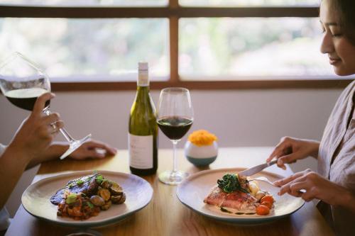 two women sitting at a table with a plate of food and wine at Ecozy Dijiwa Canggu in Canggu