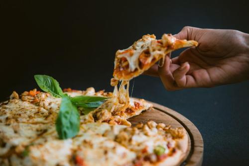 a person is holding a slice of pizza at Ecozy Dijiwa Canggu in Canggu