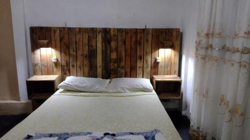 uma cama com uma cabeceira em madeira num quarto em Liart Hospedajes em Puerto Iguazú