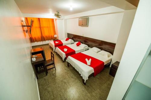 a hotel room with three beds and a table at Hotel Luxor Pucallpa in Pucallpa