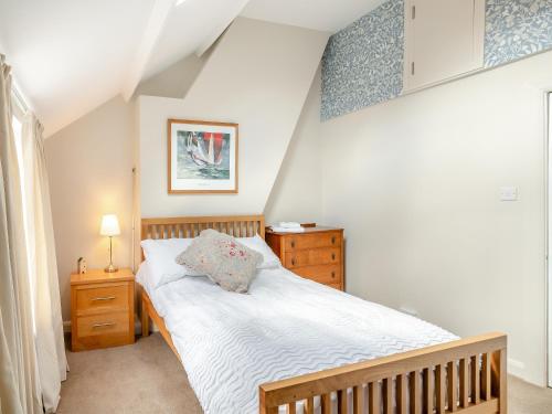 a bedroom with a white bed and a dresser and a bed sidx sidx sidx at Workshop Cottage in Rawcliffe