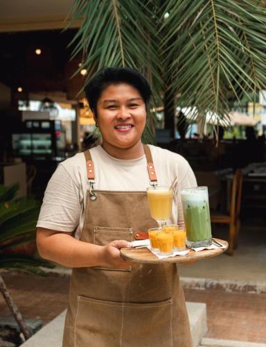 a man holding a tray of drinks on a plate at Casa Solana in Patong Beach