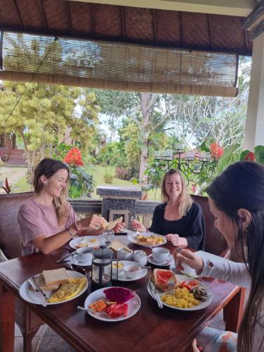 Eine Gruppe von Frauen, die an einem Tisch sitzen und Essen essen. in der Unterkunft Sava Eco Retreat in Padangan