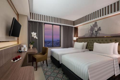 a hotel room with two beds and a television at The Alana Hotel & Conference Center Malioboro Yogyakarta by ASTON in Yogyakarta